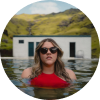 Femme en maillot de bain rouge et lunettes de soleil profitant d'une piscine d'eau chaude naturelle en Islande.