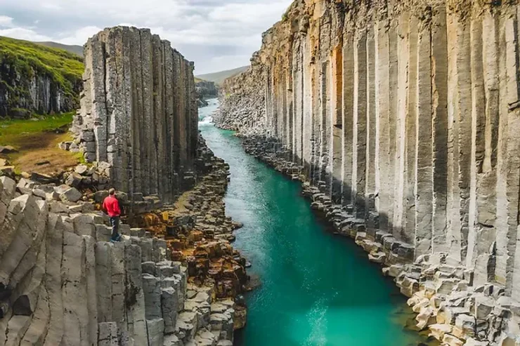 Une montagne spectaculaire se reflétant dans un lac calme, sous un ciel nuageux en Islande.