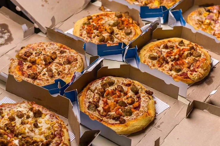 Boîtes de pizza Domino’s remplies de pizzas fraîchement préparées avec différentes garnitures savoureuses.