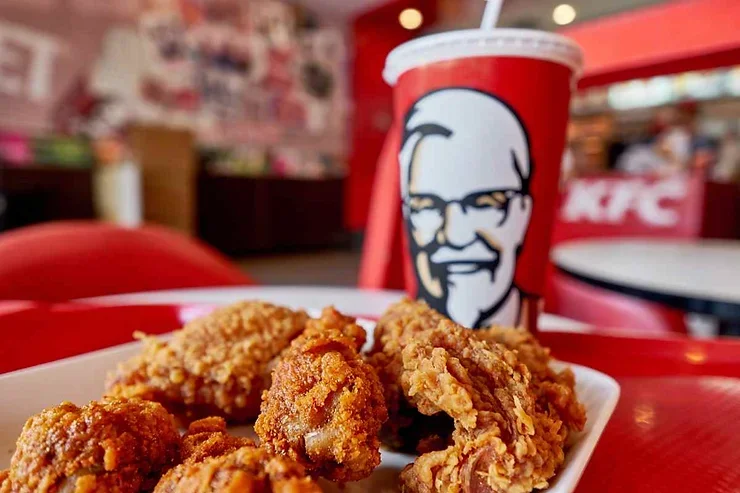 Un plat de poulet frit KFC avec une boisson gazeuse, un repas populaire et appétissant dans un cadre convivial.