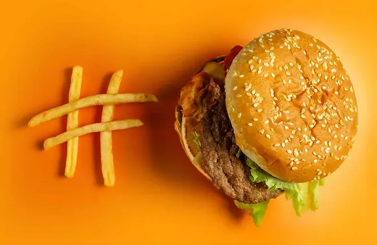 Un hamburger classique avec des frites, placé sur un fond orange vif, un symbole de fast-food.