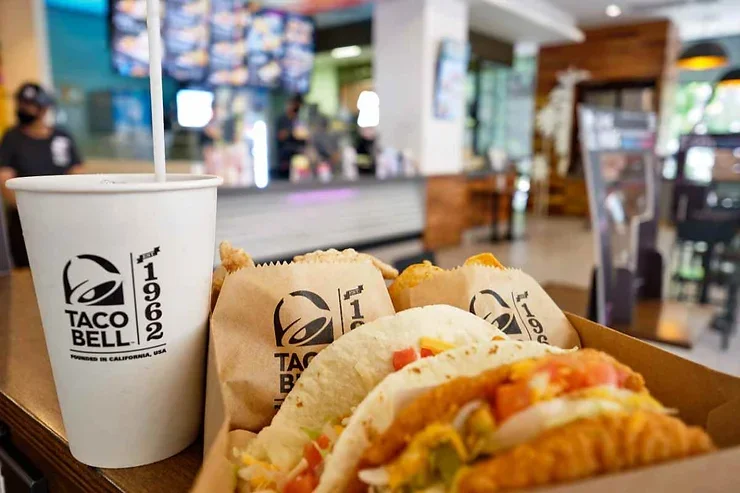 Un plateau de tacos avec une boisson gazeuse, prêt à être dégusté dans un cadre animé.