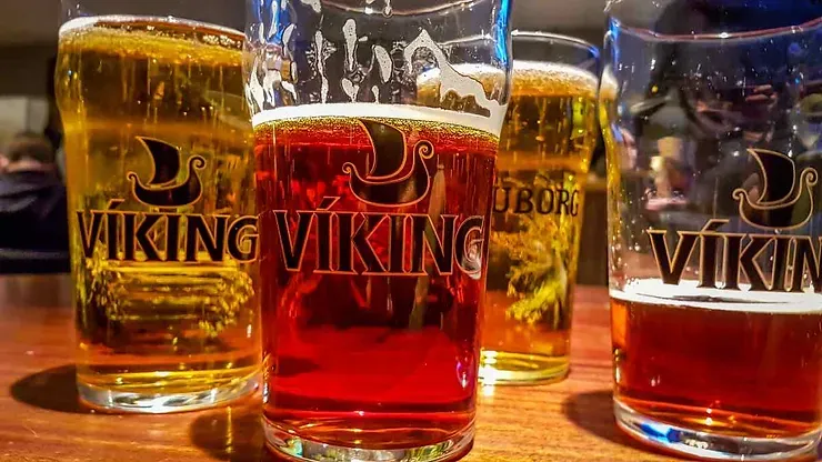 Bière artisanale islandaise Quatre verres de bière artisanale islandaise de la marque Viking, alignés sur un comptoir en bois, mettant en valeur des nuances dorées et ambrées.