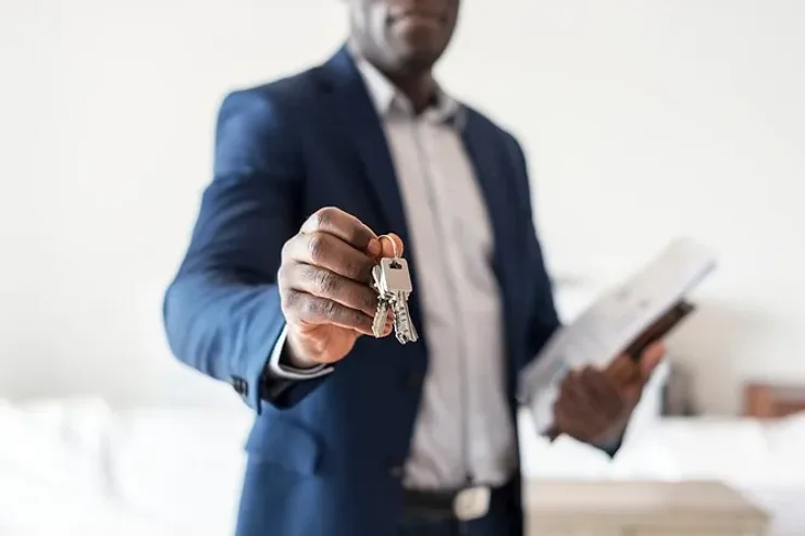 Agent immobilier tendant une clé, symbolisant l'achat de propriétés en Islande.