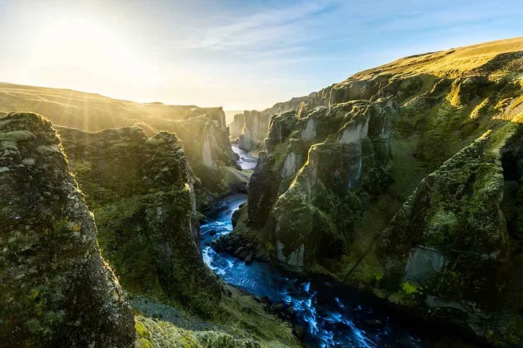 Gorge de Fjardrargljufur en Islande, entour&eacute;e de verdure et baign&eacute;e de lumi&egrave;re.