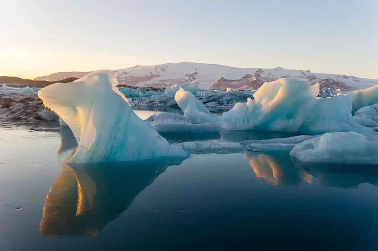Icebergs majestueux flottant dans la lagune glaciaire de J&ouml;kuls&aacute;rl&oacute;n, refl&eacute;tant le coucher du soleil sur les eaux cristallines.