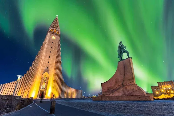 La cath&eacute;drale Hallgr&iacute;mskirkja illumin&eacute;e par les danses des aurores bor&eacute;ales dans le ciel de Reykjavik.
