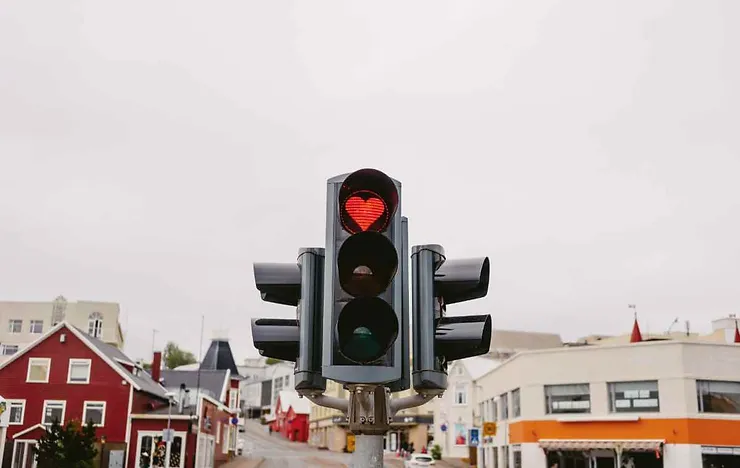 Un feu de circulation inhabituel avec un symbole de cœur rouge, dans un décor urbain coloré.
