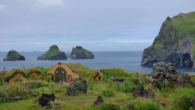 Ensemble pittoresque de petites maisons d'elfes décoratives, surplombant les îles rocheuses entourées par l'océan, en Islande.
