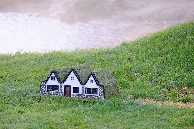 Maison miniature d'elfes islandais, recouverte de mousse, sur un terrain verdoyant, évoquant la culture folklorique locale.