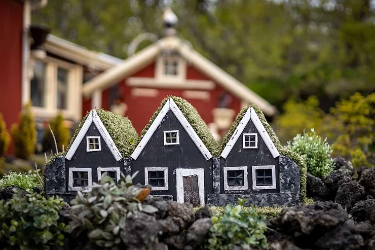 Petite maison noire d'elfes au toit en herbe, nichée dans un jardin, typique des traditions islandaises.