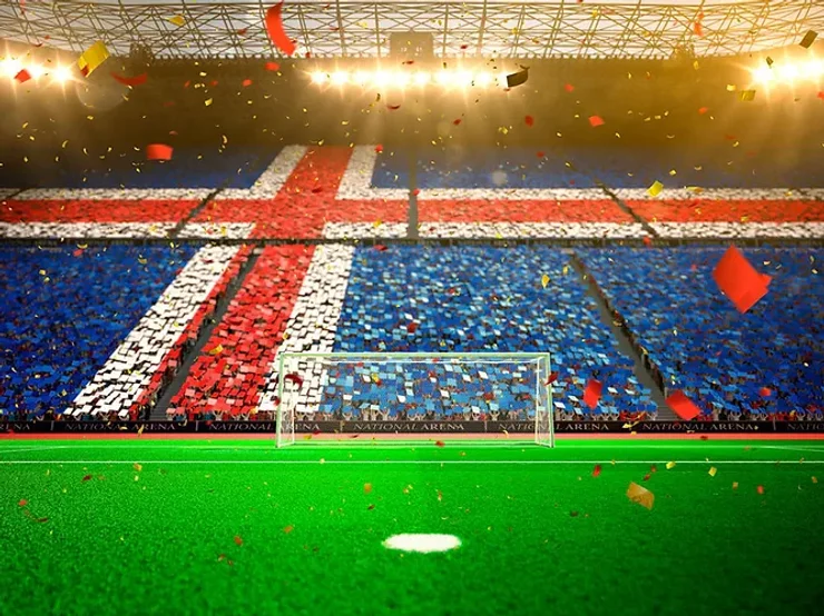 Un stade rempli de supporters, dont les tribunes forment le drapeau islandais. Au premier plan, un terrain de football, tandis que des confettis colorés tombent d'en haut.