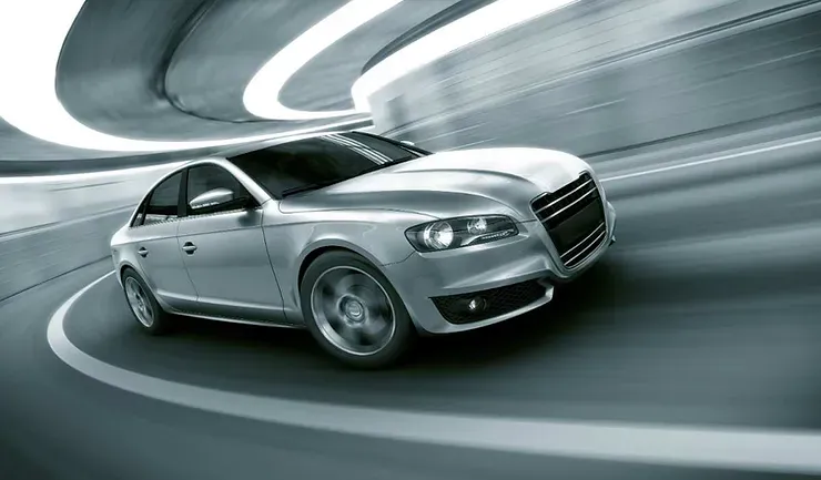Une berline argentée roulant rapidement dans un tunnel futuriste avec des lignes de lumière courbées, évoquant la vitesse et la modernité.