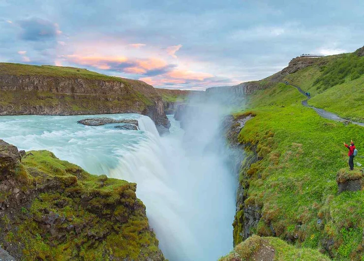  La majestueuse chute d'eau de Gullfoss en Islande au coucher du soleil, avec une personne observant la vue.