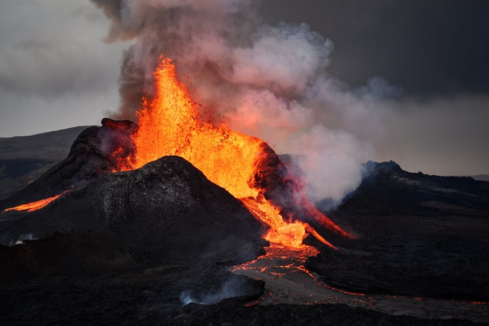 Éruption volcanique massive avec des rivières de lave incandescente et une épaisse fumée s'élevant dans le ciel.