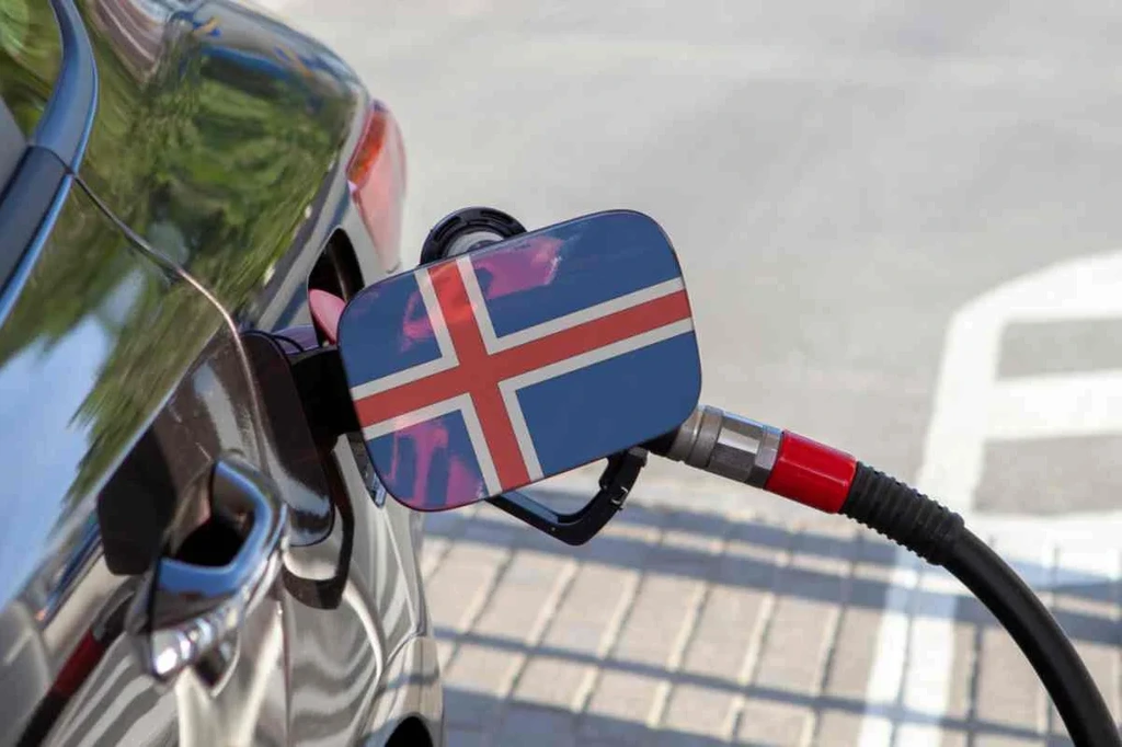Voiture faisant le plein dans une station-service avec le drapeau islandais sur le bouchon du réservoir, représentant les voyages et les transports en Islande.