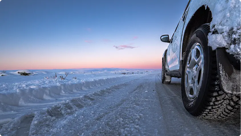Vue aérienne d'une route traversant des champs de lave sombres avec de l'eau géothermique bleue vibrante à proximité, mettant en valeur les paysages uniques accessibles depuis Reykjavik avec une voiture de location.