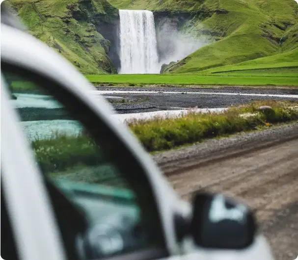 Vue de la cascade Skógafoss depuis une voiture stationnée – symbole de notre engagement qualité.