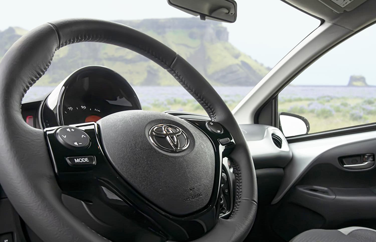 Toyota Aygo orange vif avec boîte automatique, idéale pour 4 passagers, compacte et efficace pour les déplacements en ville en Islande.