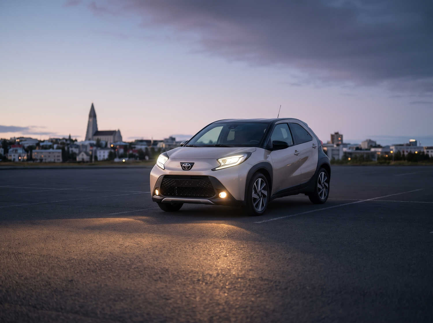 Toyota Aygo orange vif avec boîte automatique, idéale pour 4 passagers, compacte et efficace pour les déplacements en ville en Islande.