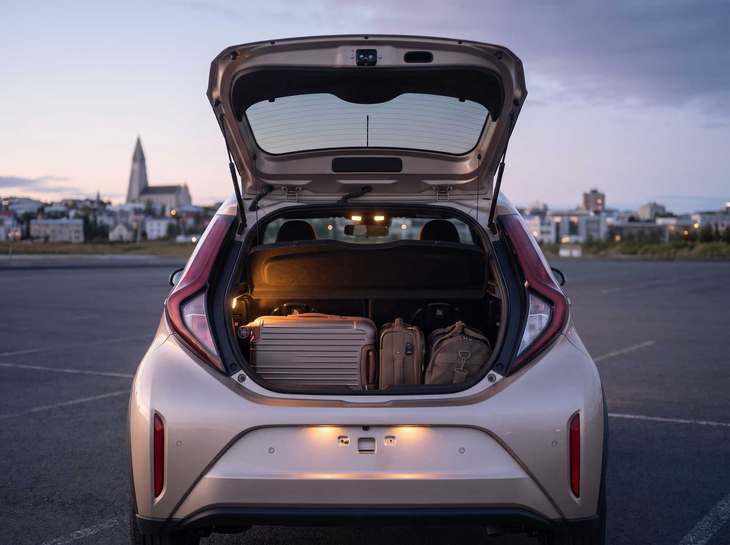 Toyota Aygo orange vif avec boîte automatique, idéale pour 4 passagers, compacte et efficace pour les déplacements en ville en Islande.