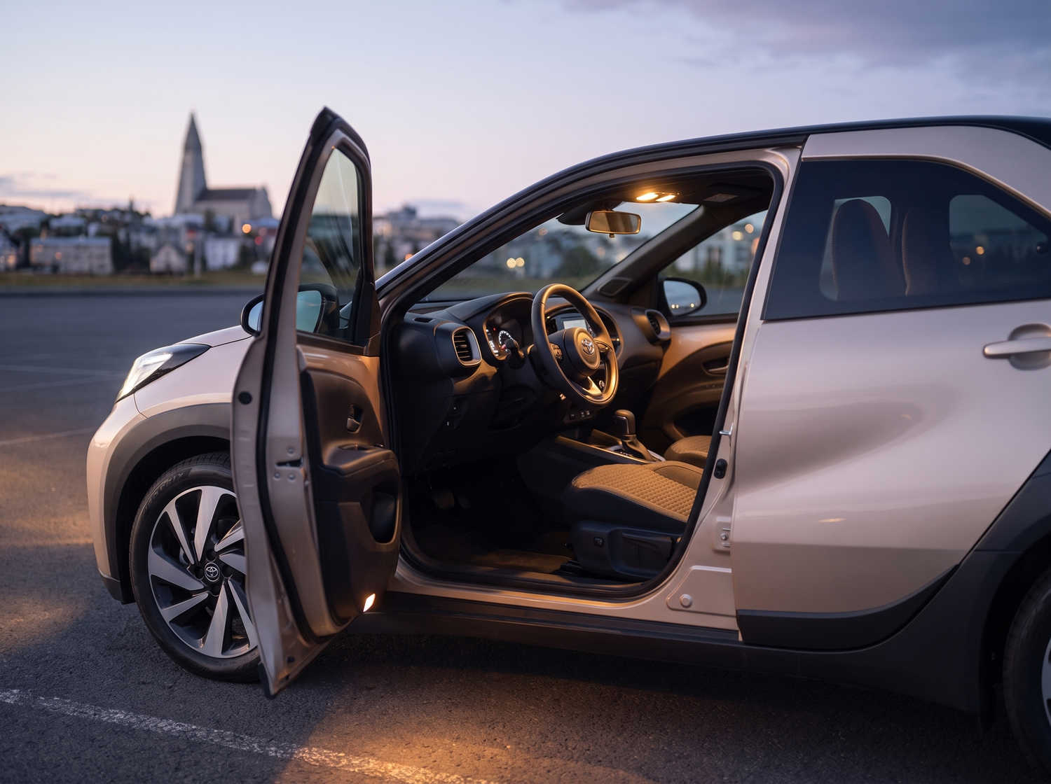 Toyota Aygo orange vif avec boîte automatique, idéale pour 4 passagers, compacte et efficace pour les déplacements en ville en Islande.