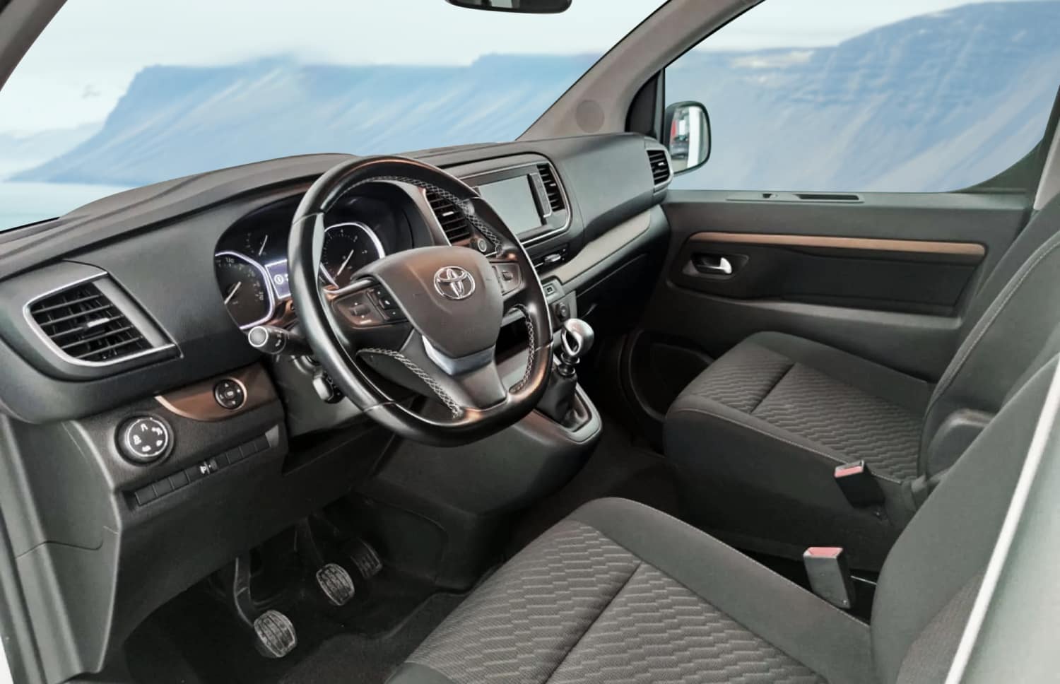 Toyota Proace argentée, van 9 places avec boîte automatique, GPS, Bluetooth, sièges chauffants et chargeur USB pour les voyages en groupe en Islande.