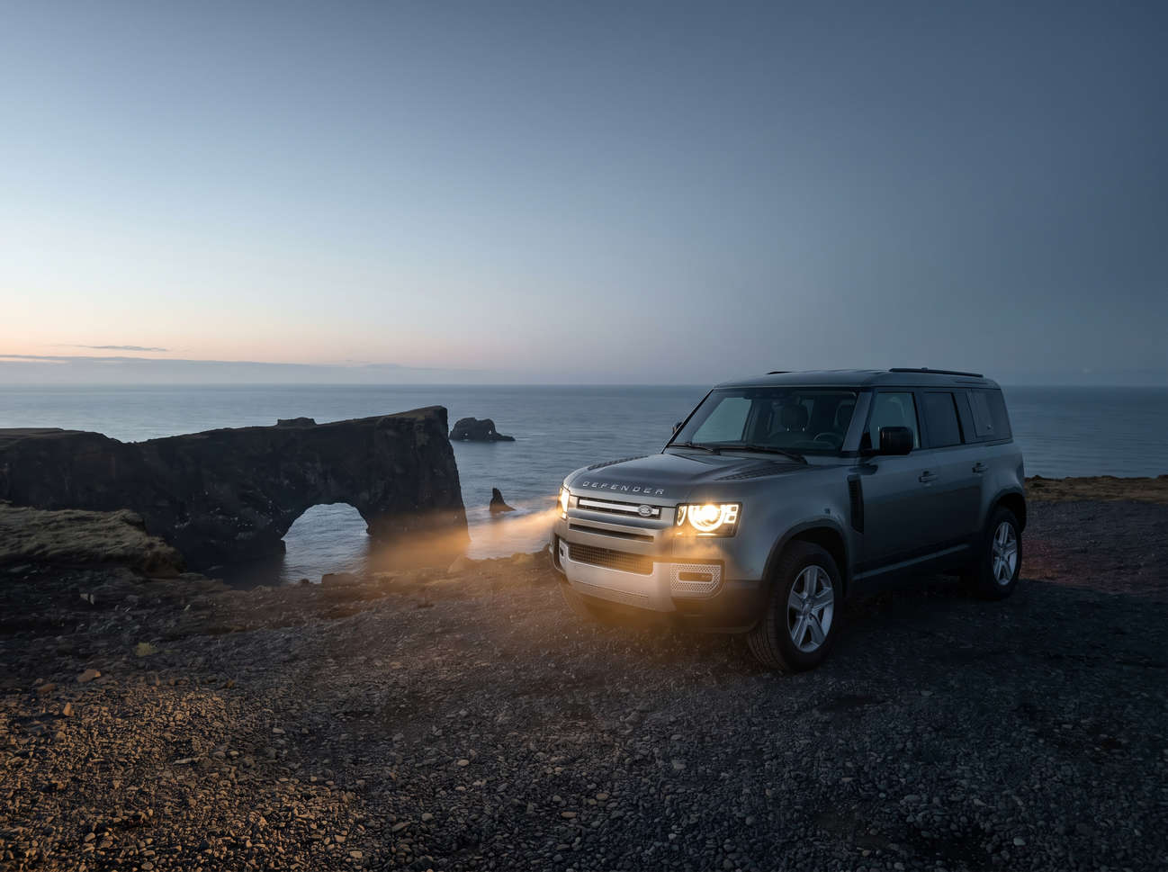 Land Rover Defender gris, SUV 4x4 de luxe avec GPS, sièges chauffants, chargeur USB et caméra de recul, parfait pour les routes accidentées d’Islande.