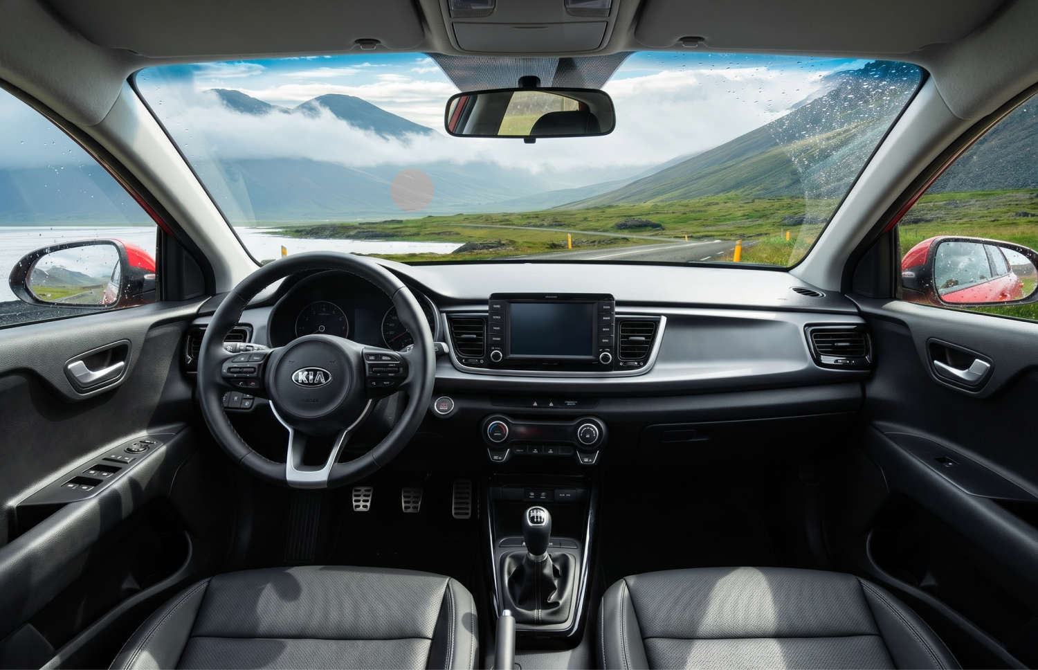 Kia Rio bleue avec boîte manuelle, GPS, caméra de recul et espace pour 5 passagers et 2 bagages, parfaite pour les road trips en Islande.