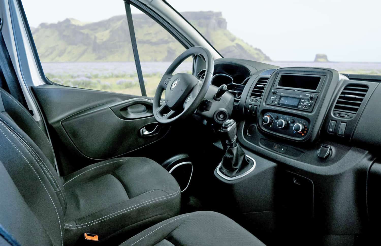Renault Trafic rouge, van 9 places avec boîte manuelle, sièges chauffants, Bluetooth et chargeur USB, parfait pour les déplacements en groupe en Islande.