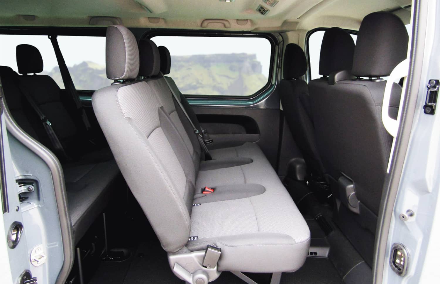 Renault Trafic rouge, van 9 places avec boîte manuelle, sièges chauffants, Bluetooth et chargeur USB, parfait pour les déplacements en groupe en Islande.