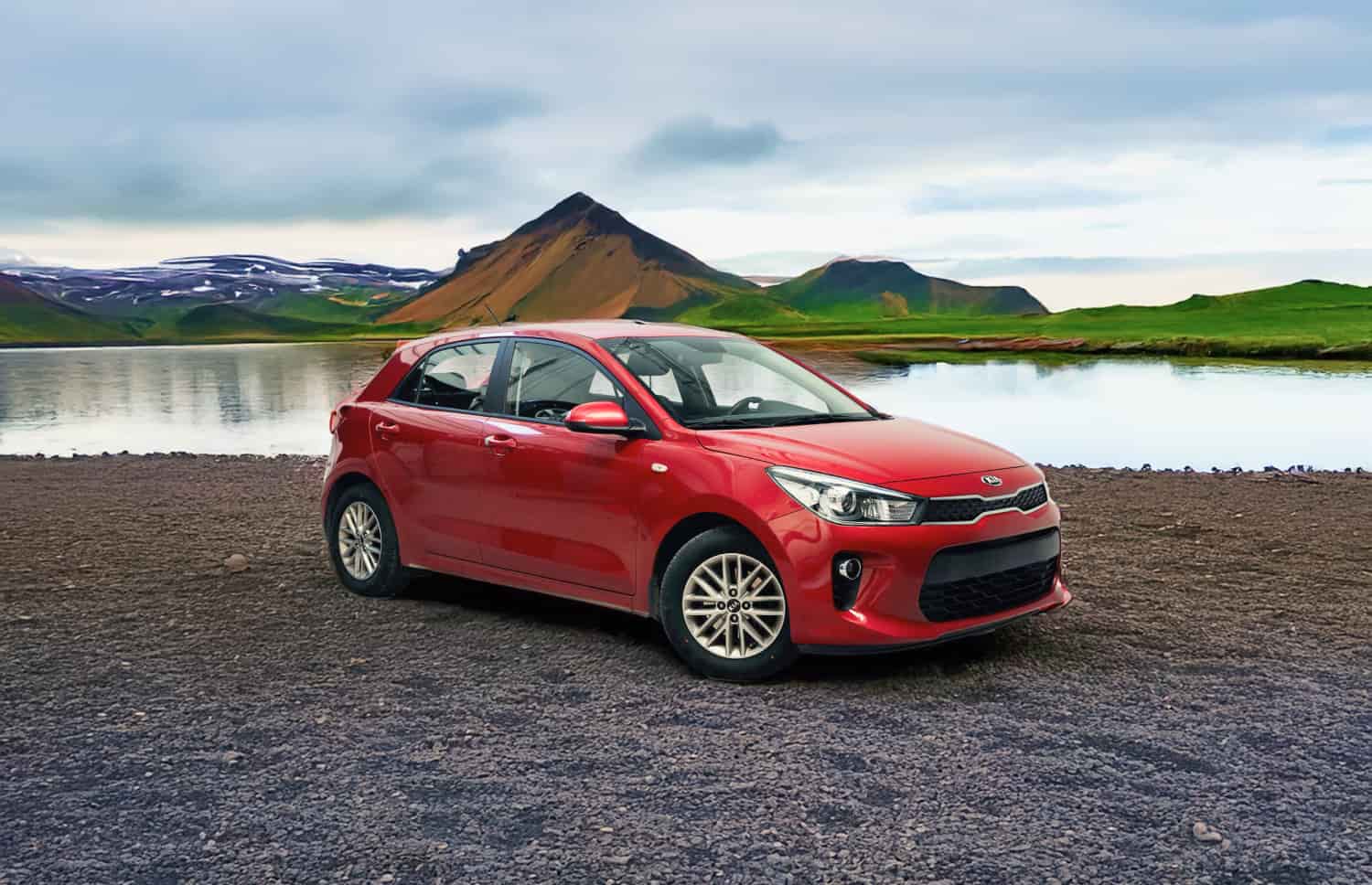 Kia Rio rouge d’occasion avec boîte manuelle, compacte 5 places avec espace pour 2 bagages, parfaite pour un voyage abordable en Islande.